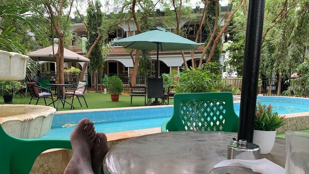 Uma área à beira da piscina com mesa, cadeiras e piscina.