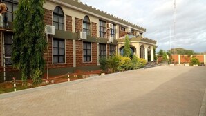 Um edifício com vários andares, fachada de tijolos, janelas amplas e aparelhos de ar condicionado.