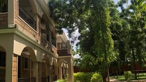 Um edifício com vários andares e um pátio central, rodeado por vegetação exuberante e árvores.
