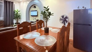 A dining area with a wooden table, chairs, and a central potted plant. - The Terrace condominium baguio city (Baguio)