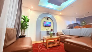 A modern living room with leather sofas, a wooden coffee table, and a flat-screen TV mounted on an arched wall. - The Terrace condominium baguio city (Baguio)
