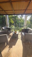 Un espacio de descanso al aire libre con mobiliario de mimbre y una planta en maceta.