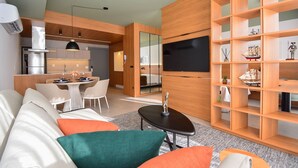 Uma sala de estar moderna com um sofá, mesa de centro e uma TV fixada numa parede de madeira.