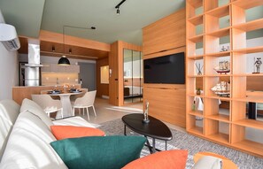 Una sala de estar moderna con un sofá, una mesa de centro y un televisor montado en una pared de madera.