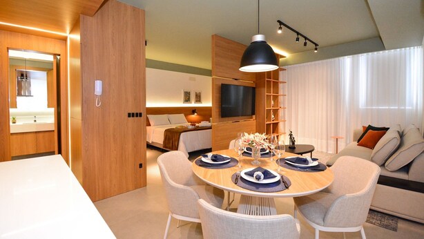 Un salon moderne comprenant un coin repas, un canapé, un téléviseur et un mur d’accent en bois.