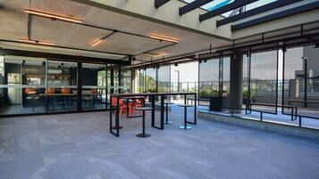 An indoor area with tables and chairs, large windows, and a view of the outdoors.