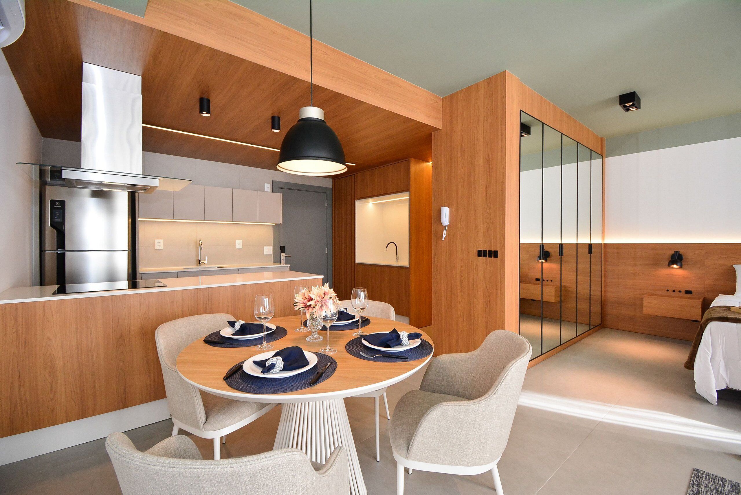 A modern kitchen with a dining area, wooden cabinetry, and a large mirror.