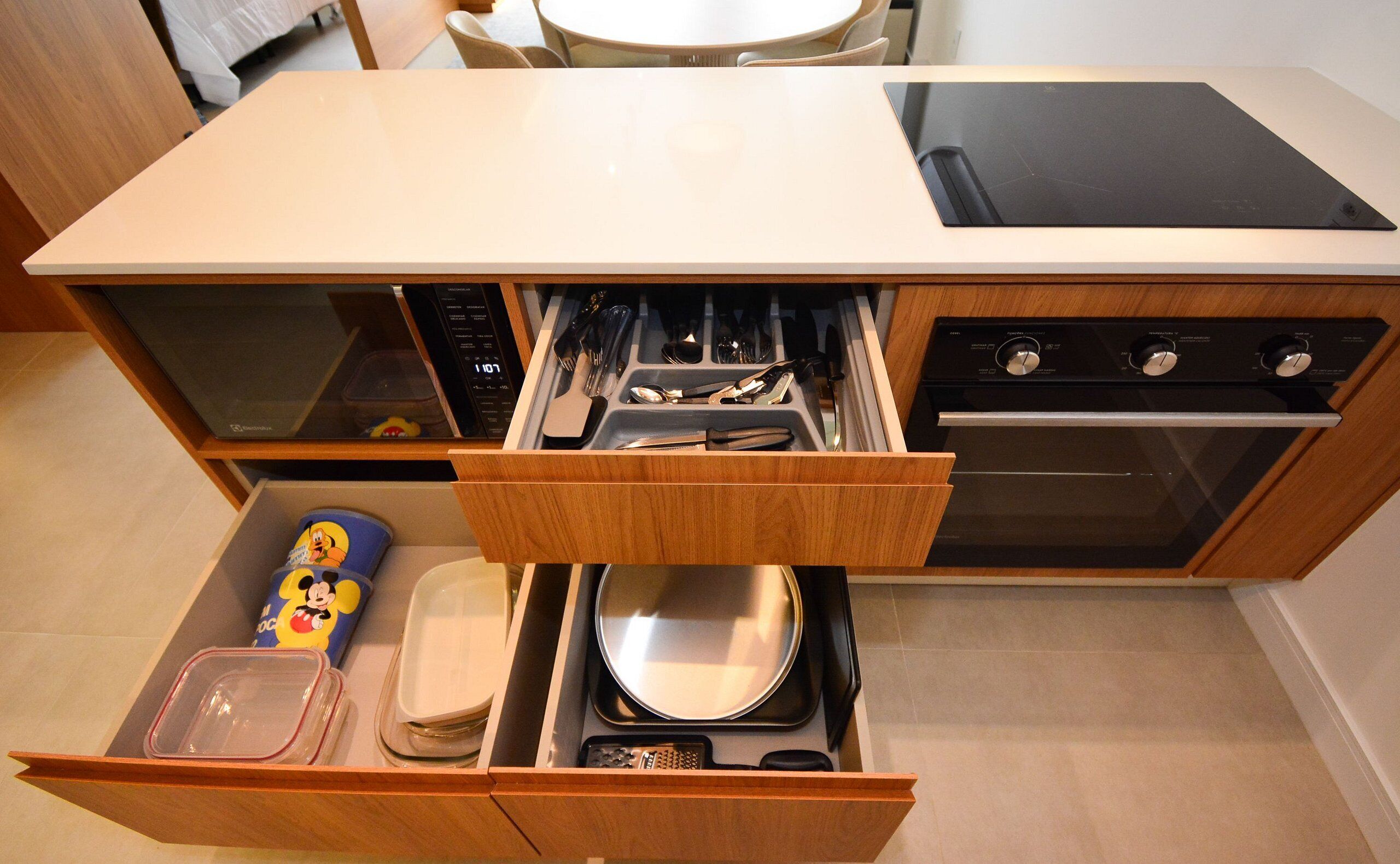 A kitchen with a built-in microwave, oven, and a drawer with utensils.