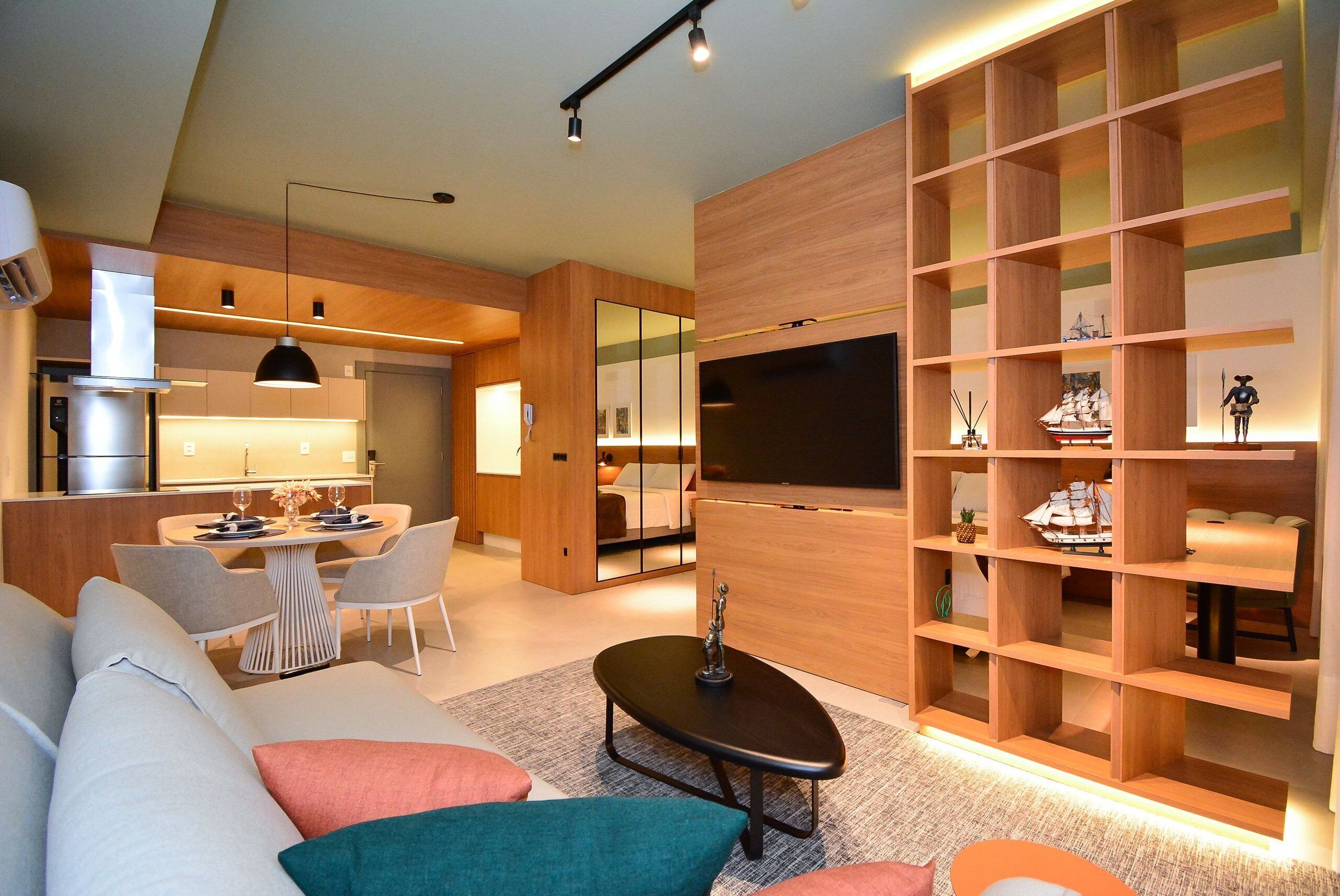 A modern living room with a sofa, coffee table, and a TV wall unit with shelves.