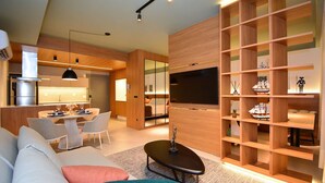 Uma sala de estar moderna com sofá, mesa de centro e painel de TV com prateleiras.