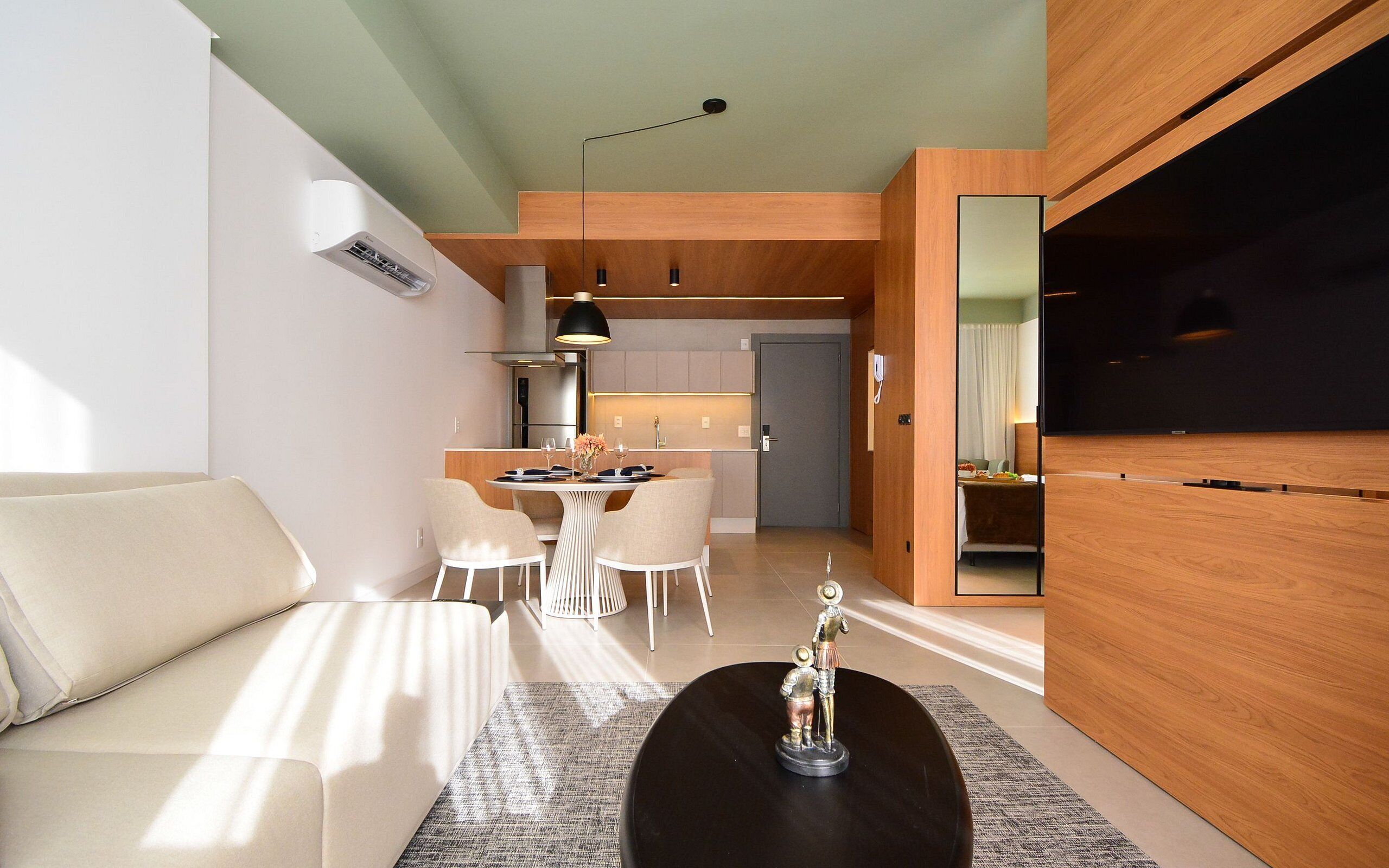 A modern living room with a sofa, a coffee table, and a dining area with chairs and a table.