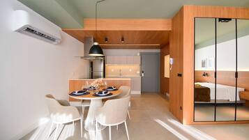 Una cocina moderna con armarios de madera, un comedor con mesa y sillas redondas, y un dormitorio con puerta corredera.