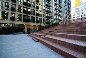 A modern building with multiple balconies, a staircase, and a flat area with a railing. - Studio em frente a UFSC e HU - CEN010 (Florianópolis)