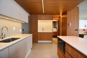 Una cocina moderna con lavavajillas incorporado, un lavamanos de acero inoxidable y muebles de madera.