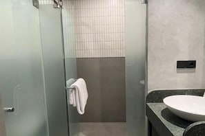 Une salle de bain moderne avec une douche à parois de verre, un lavabo blanc et un porte-serviettes.