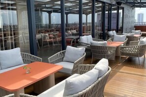 Un espace extérieur aménagé avec des meubles en osier et des cloisons en verre.