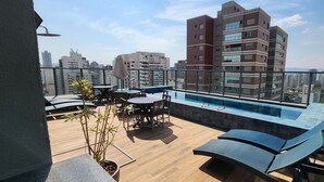 A rooftop terrace with a pool, lounge chairs, and a dining area. - Comfortable studio apartment in Perdizes - Allianz Parque with pool and rooftop. (São Paulo)
