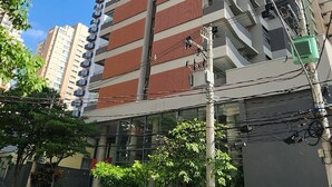 A multi-story building with a modern design, featuring a mix of red and grey facade, and several balconies. - Comfortable studio apartment in Perdizes - Allianz Parque with pool and rooftop. (São Paulo)