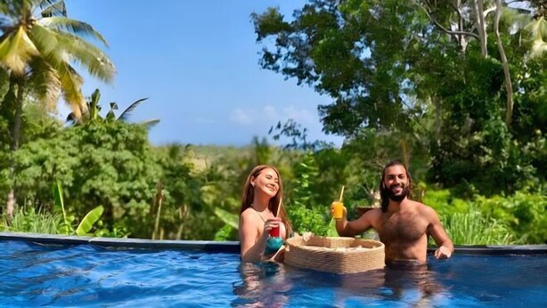 A swimming pool with two people, surrounded by lush greenery. - Meket Bungalows (Bali)