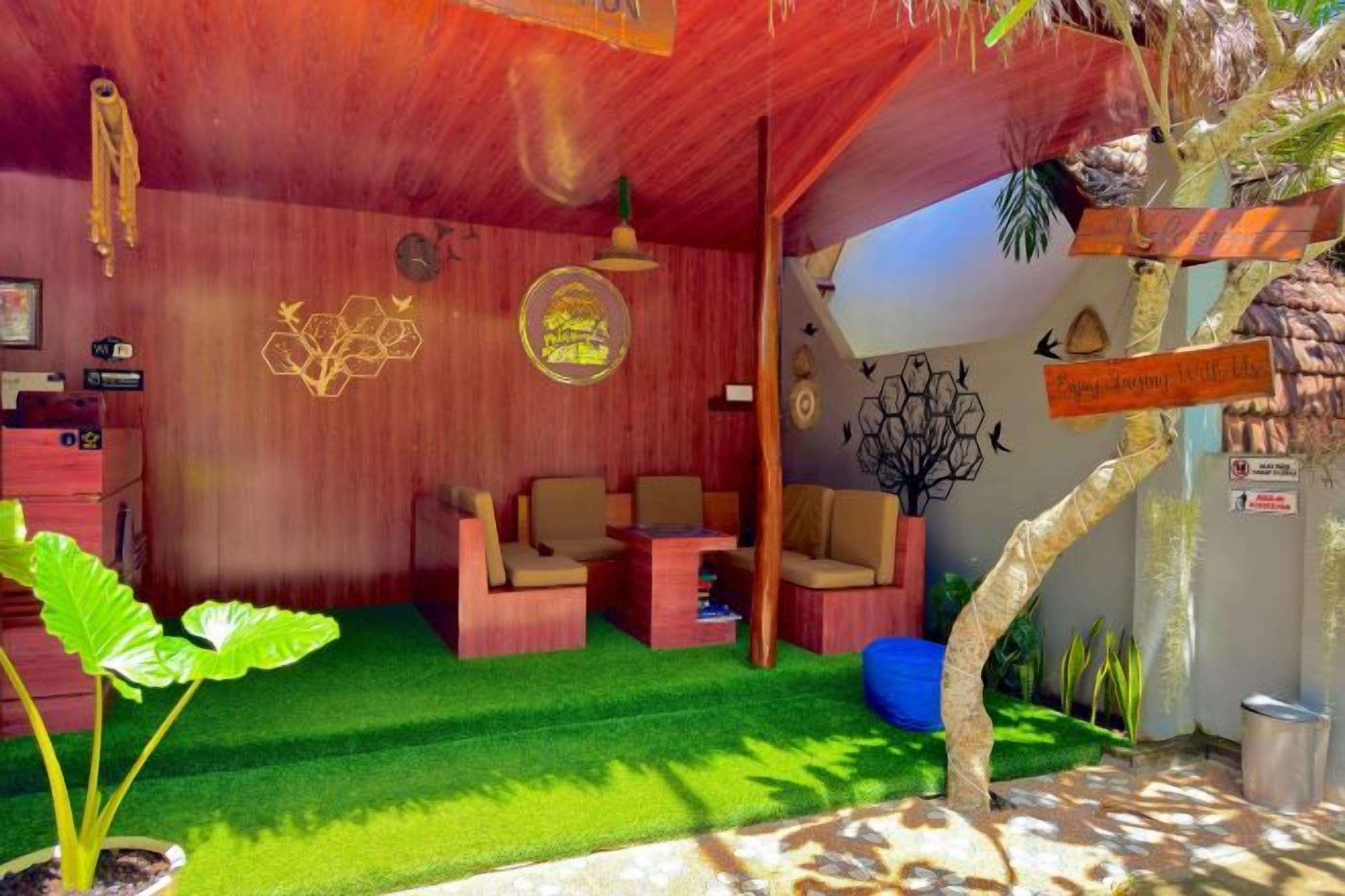 A room with a wooden ceiling, green artificial grass, two sofas, a coffee table, and a small plant.