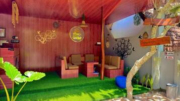 Una habitación con techo de madera, césped artificial verde, dos sofás, una mesa de centro y una planta pequeña.