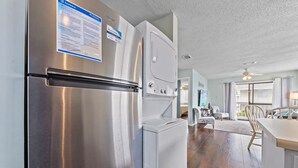 A modern kitchen with stainless steel appliances, a built-in washer and dryer, and a view to the living area. - Wolf Bay Villas 208: Waterfront (Orange Beach)