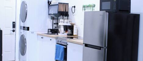 A modern kitchen with a washing machine, oven, refrigerator, and microwave.
