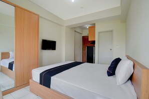 A hotel room with a single bed, a flat-screen TV mounted on the wall, and a wooden wardrobe. - OYO 94837 Apartment Ekki Tower (Gunung Putri)