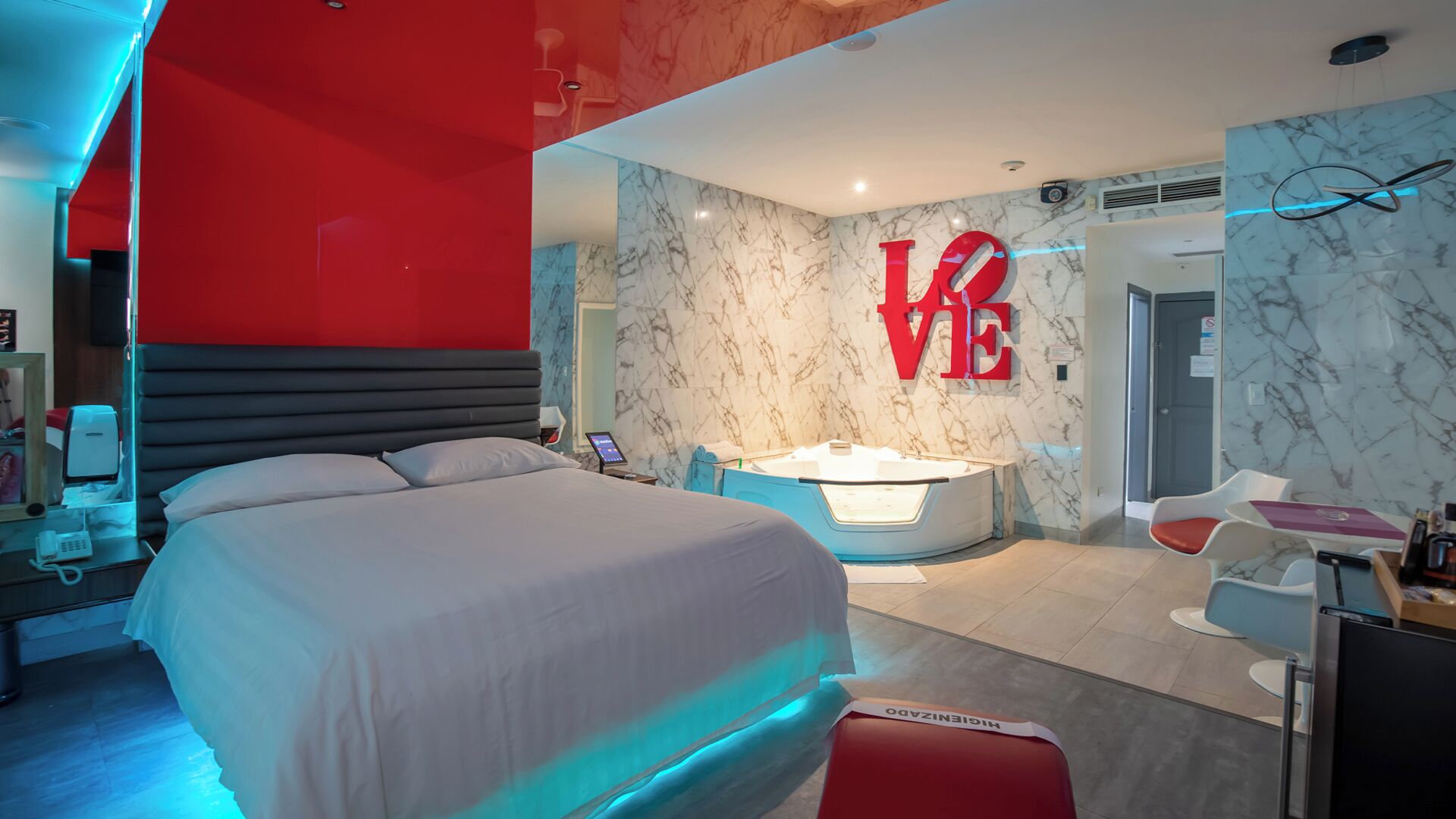 Una habitación de hotel moderna con una cama grande, un jacuzzi y un cartel con la palabra 'LOVE'.