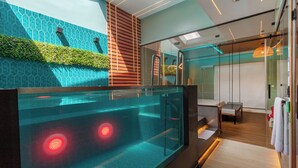A modern hotel room with a glass-enclosed pool, a wooden slatted wall, and a glass partition separating the pool from the bedroom area. - Liv Motel Ecuador (Quito)