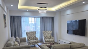 A modern living room with a sofa set, a coffee table, and a flat-screen TV mounted on the wall. - Marina Bay Suites (Nairobi)
