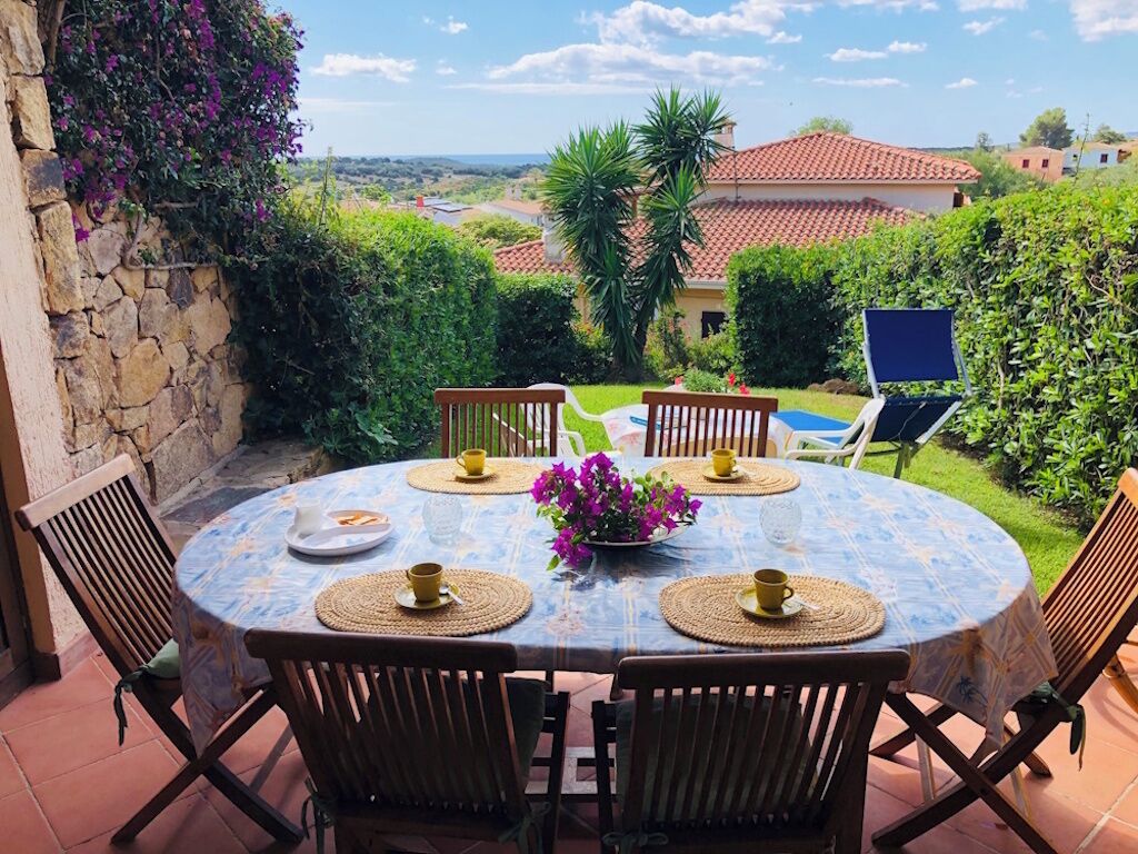 Une table ronde avec quatre chaises, une nappe bleue et un vase rempli de fleurs violettes.