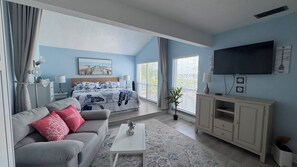Een slaapkamer met een bed, een televisie, een bank en een raam.