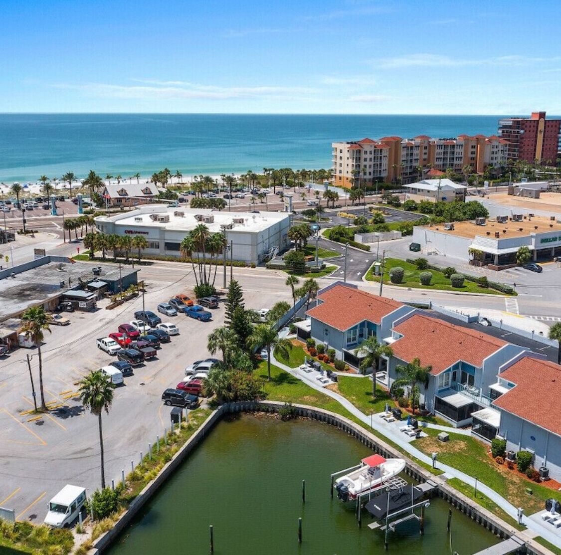 A coastal hotel with a marina, parking lot, and beachfront view.
