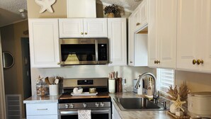Una cucina moderna con mobili bianchi, elettrodomestici in acciaio inossidabile e un piano di lavoro in marmo.