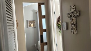Un corridoio con una porta in legno, una croce appesa al muro e una decorazione a stella marina.