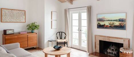 A living room with a sofa, a coffee table, a fireplace, a cabinet, and a painting.