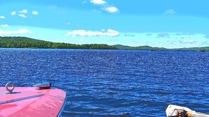A lake with a boat docked on the left. - Fern - Big Moose Lakeside (Eagle Bay)