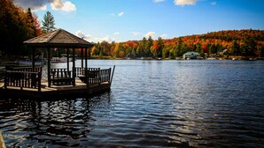 A wooden gazebo with benches on a lake, surrounded by autumn-colored trees and a clear sky. - Fern - Big Moose Lakeside (Eagle Bay)