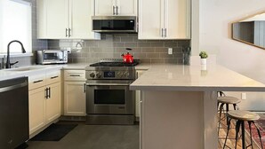 A modern kitchen with white cabinets, stainless steel appliances, a built-in microwave, and a red kettle on the stove. - Snow Summit Cabin Big Bear- 25ft to Snow Summit! (Big Bear Lake)