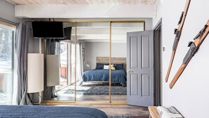 A bedroom with a bed, a TV, a sliding door, and skis on the wall. - Snow Summit Cabin Big Bear- 25ft to Snow Summit! (Big Bear Lake)