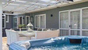A spa area with a hot tub, outdoor seating, and string lights. - Bayfair Break - Mt Maunganui (Mt Maunganui)