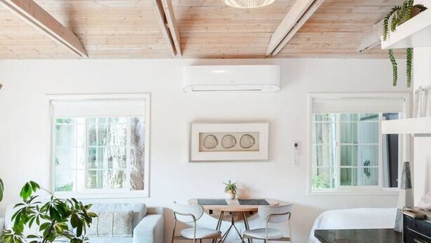 Una cocina moderna con vigas de madera, una zona de comedor con mesa y sillas, y un ventanal grande.