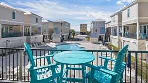 A pool area with turquoise chairs and tables, surrounded by multi-story buildings with balconies. - New! Steps to Beach & Lagoon~Pool~Family Fun~Paddle Boards (Gulf Shores)