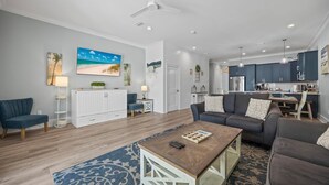 A spacious living room with a large sofa, a coffee table, and a dining area. - New! Steps to Beach & Lagoon~Pool~Family Fun~Paddle Boards (Gulf Shores)