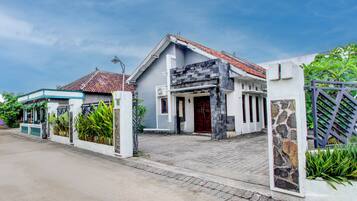 A two-story house with a tiled roof, a stone pillar, and a gated entrance.