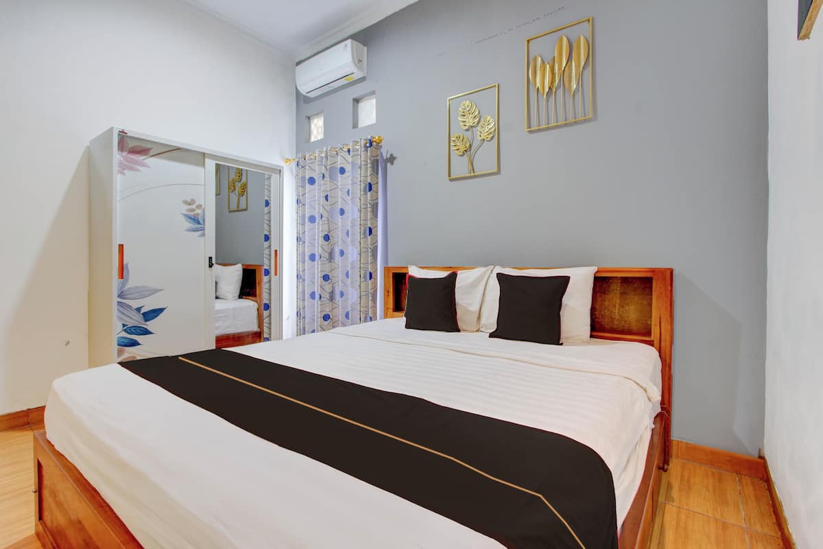 Un dormitorio con cama, armario, cortina de ducha y cuadros en la pared.
