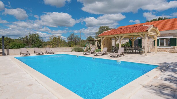 A rectangular swimming pool with lounge chairs and a covered seating area. - 4-bedroom villa in beautiful Ljubotić with AC, Rural Villa Olive Krka (Ljubotić)