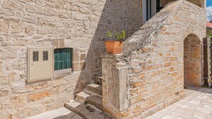 A stone building with a small staircase leading to a door, a window with green shutters, and a potted plant on the steps. - 4-bedroom villa in beautiful Ljubotić with AC, Rural Villa Olive Krka (Ljubotić)