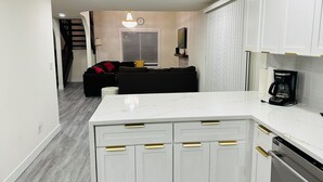 Una cocina moderna con armarios blancos, encimera de mármol y lavavajillas integrado.